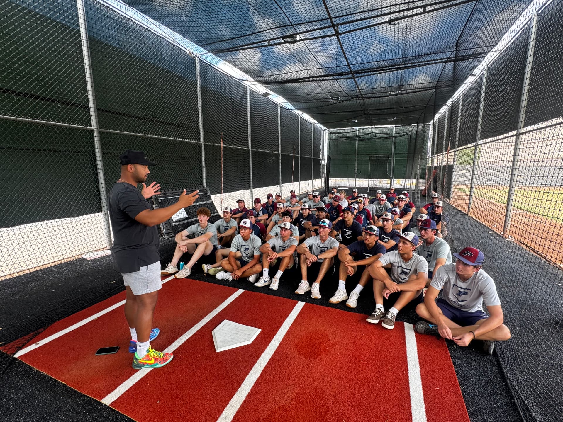 Jamie speaking to a baseball team in the batting cage